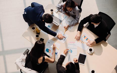A group of people in a business meeting discussing figures around a table