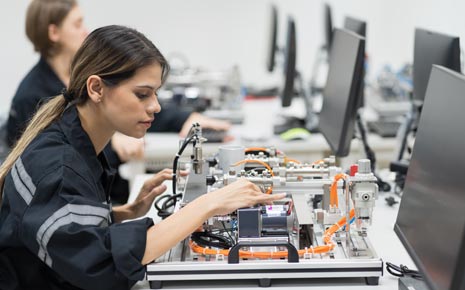 A female engineering student works on an electrical board project in class